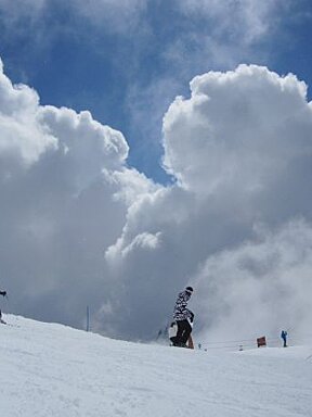 People skiing down a snow covered slope with a sign that says ' ski ' on it