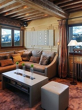 image of a chalet living area with brown sofas and a view of the mountains